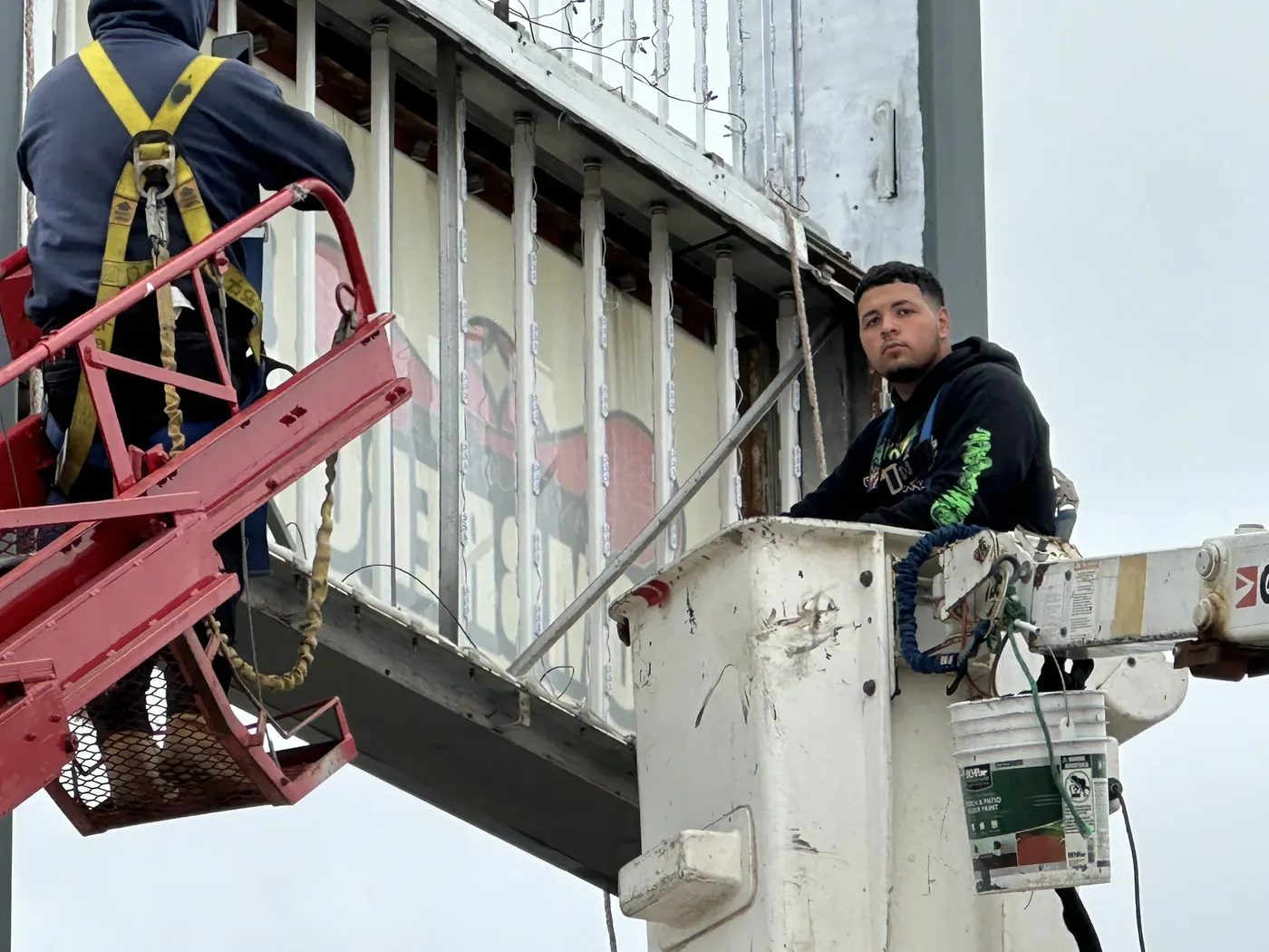 Crew working inside a sign cabinet from a lift and a bucket truck