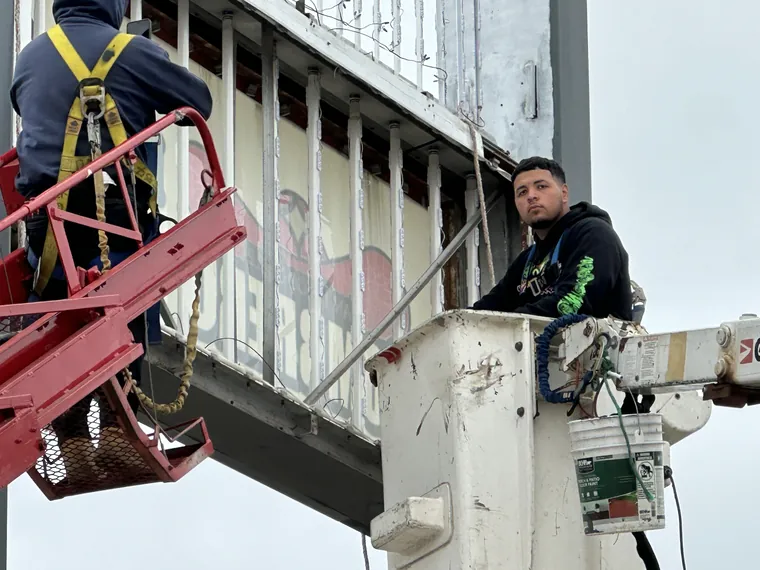 Crew working inside a sign cabinet from a lift and a bucket truck
