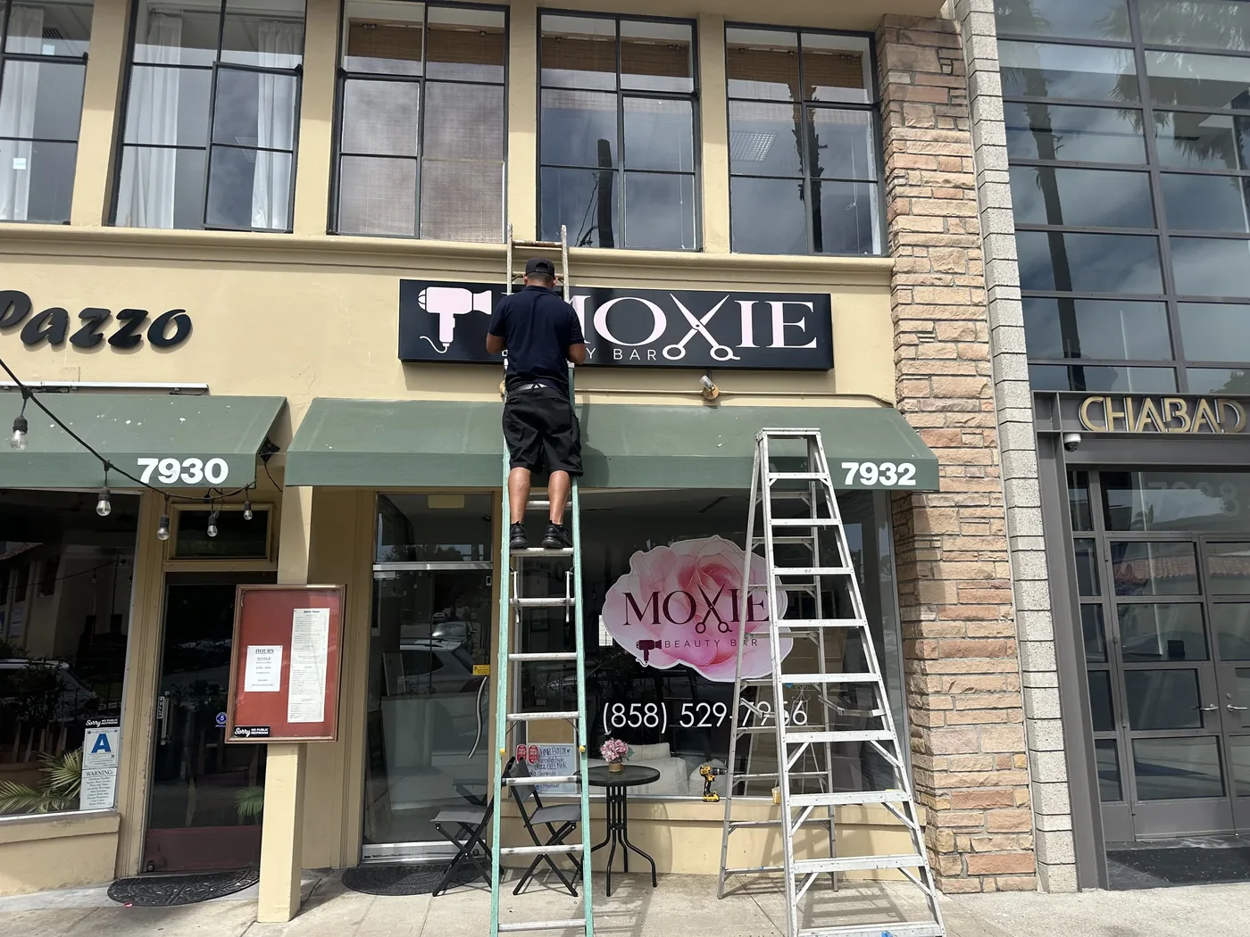 Installer fitting the Moxie Beauty Bar storefront sign