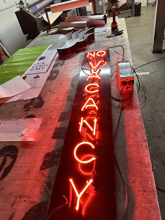No Vacancy neon sign lit on the shop bench