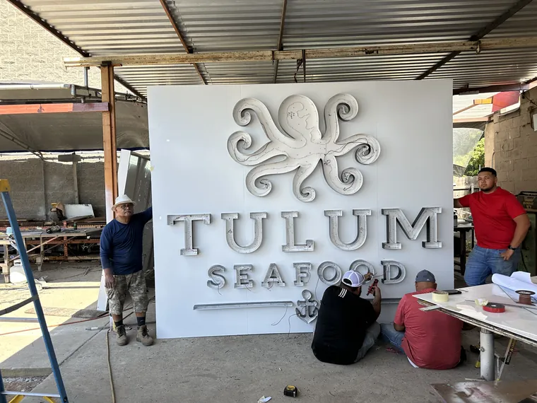 Crew assembling the Tulum Seafood sign in the shop