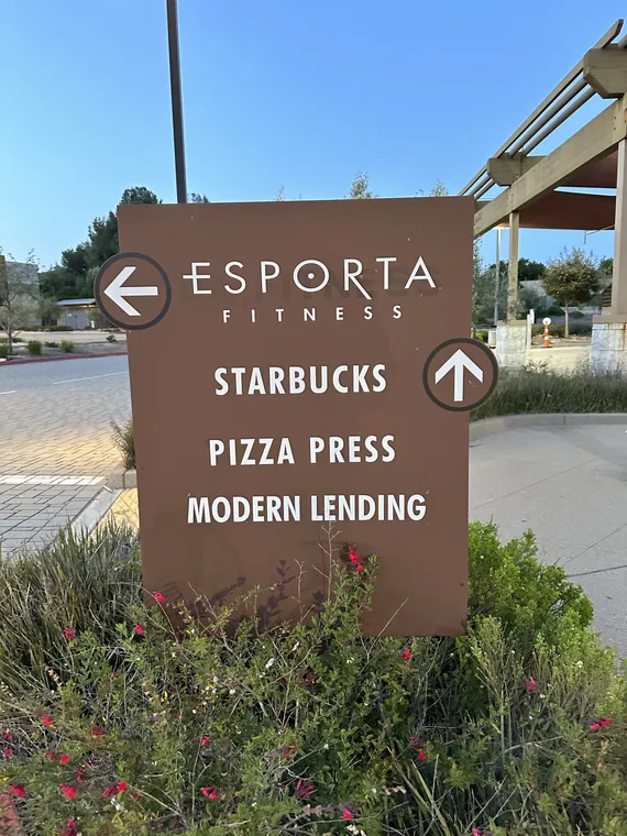 Directory sign with arrows for Esporta Fitness, Starbucks, Pizza Press and Modern Lending