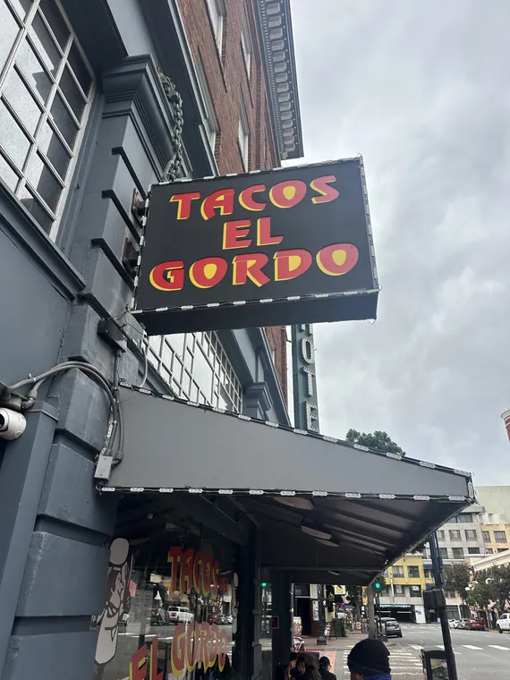 Tacos El Gordo blade sign above the sidewalk
