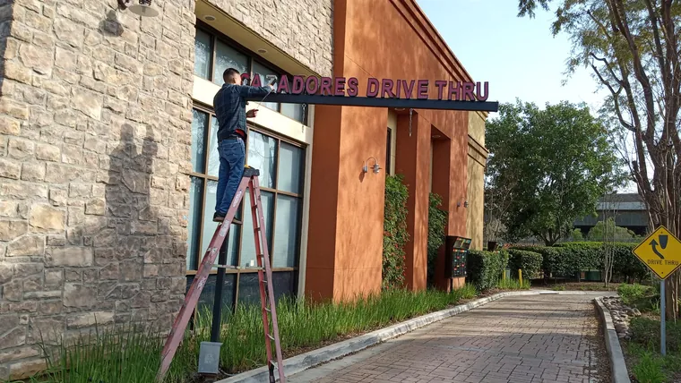 Installer fitting the Cazadores drive-through letters
