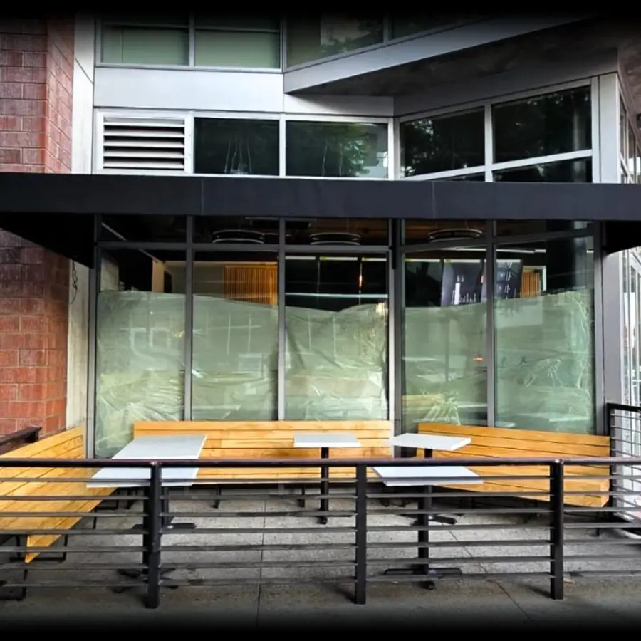 Glass patio enclosure with bench seating outside a restaurant