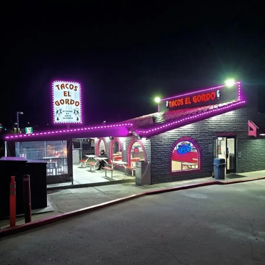 Tacos El Gordo storefront lit at night with a pylon sign and covered patio