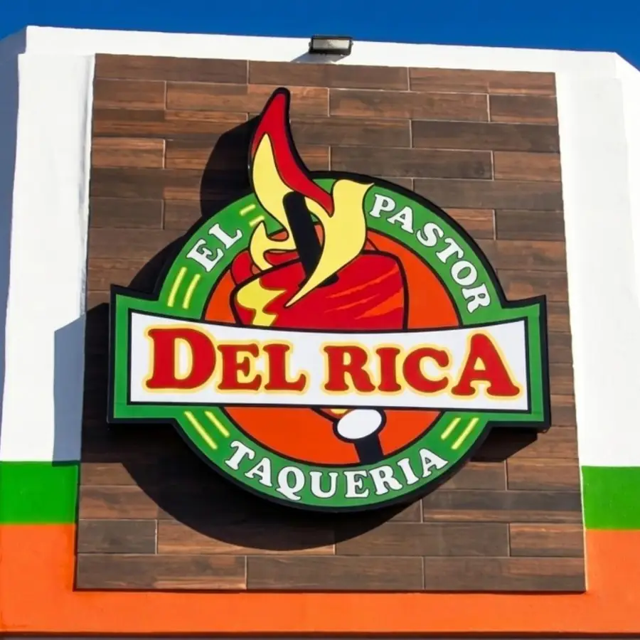 El Pastor Del Rica Taqueria logo sign mounted on a wood panel wall