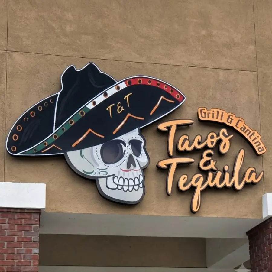 T and T Tacos and Tequila skull and sombrero logo sign on a stucco wall