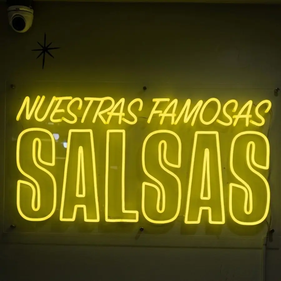 Yellow Nuestras Famosas Salsas neon sign on a restaurant wall