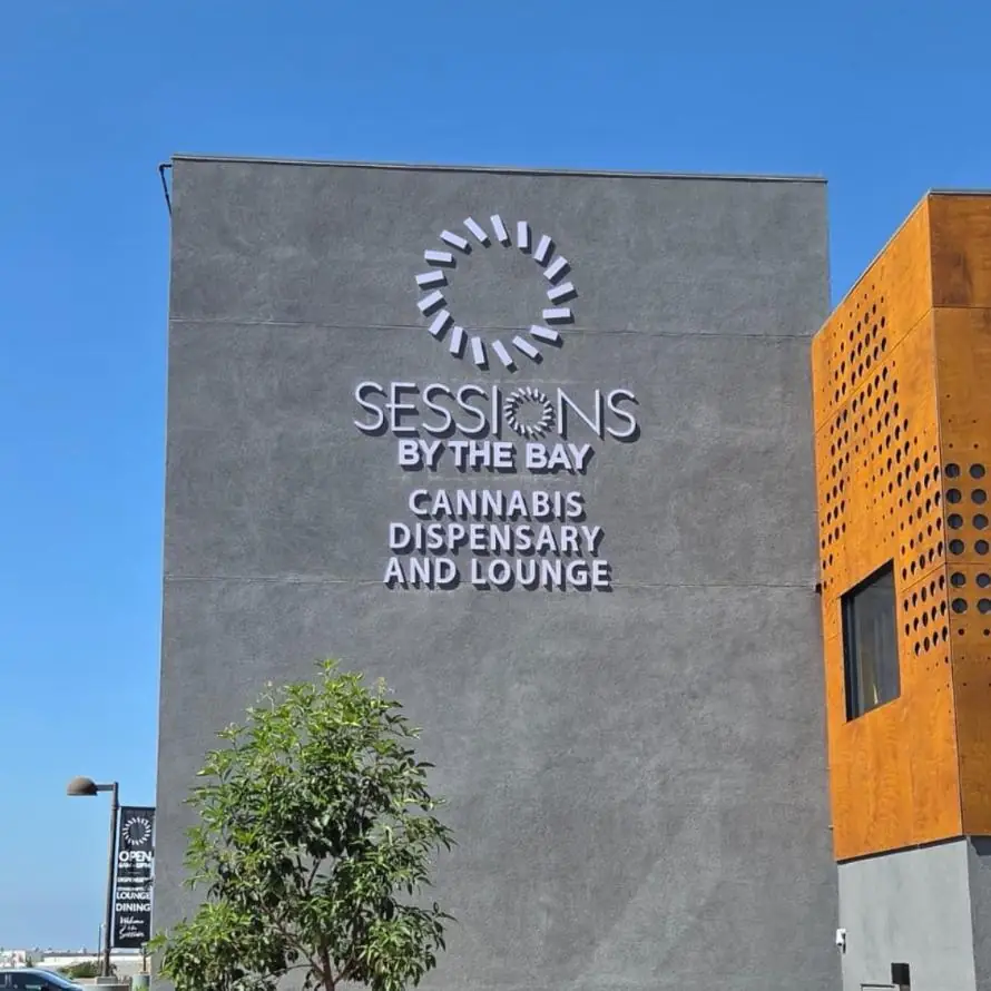 Sessions by the Bay cannabis dispensary sign high on a stucco wall