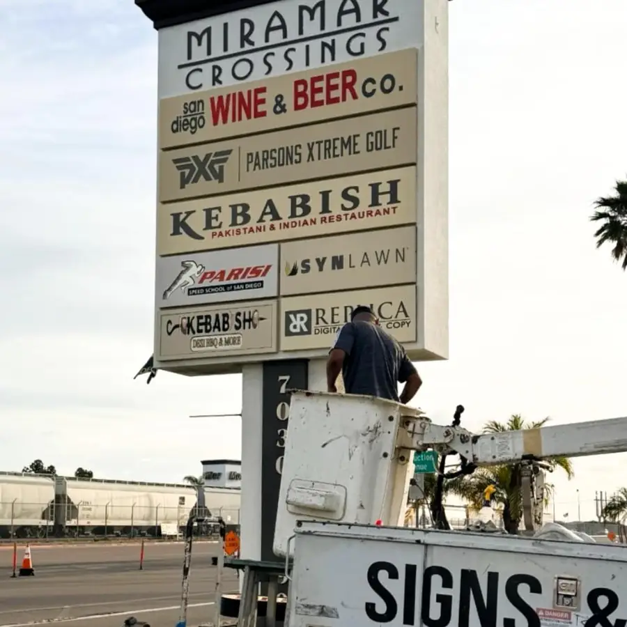 Crew replacing tenant panels on the Miramar Crossings pylon sign from a bucket truck