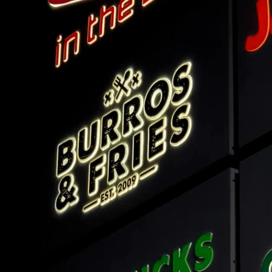 Burros and Fries panel lit on a multi-tenant pylon sign at night
