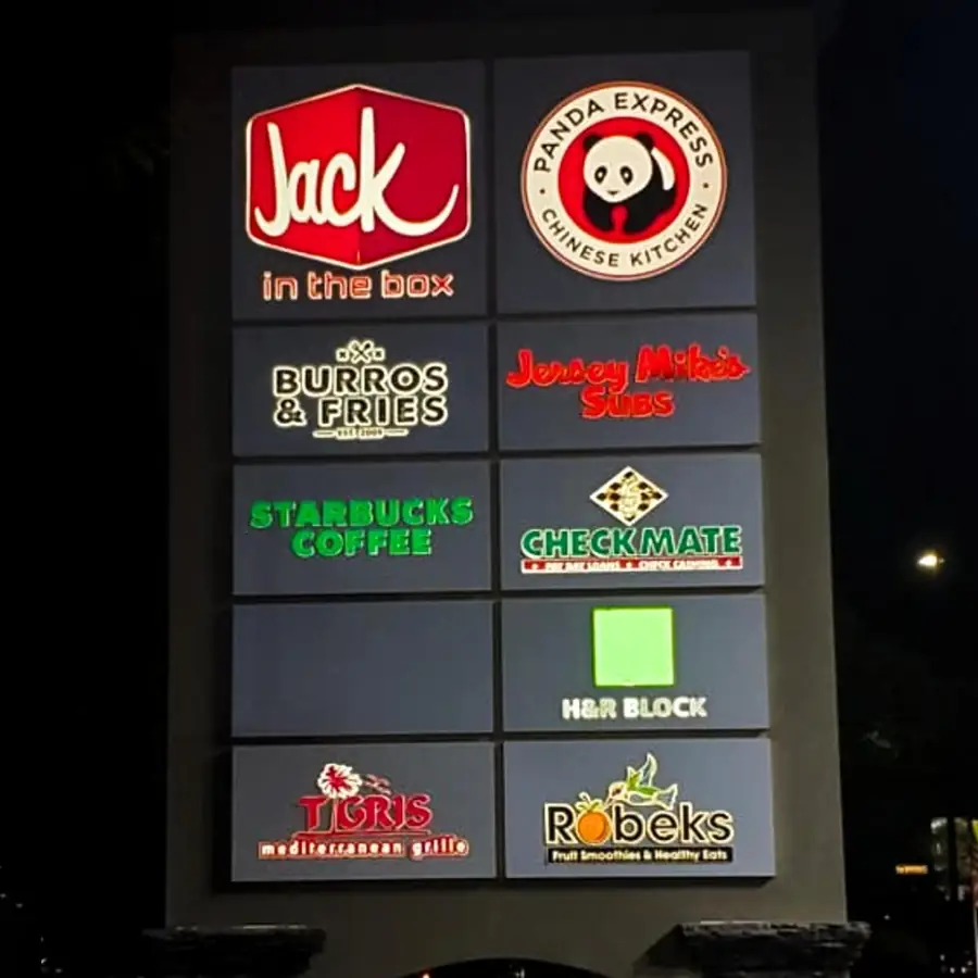 Multi-tenant pylon sign lit at night with Jack in the Box, Panda Express and Starbucks panels