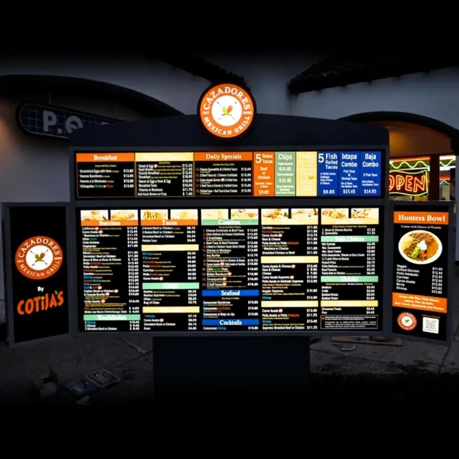 Cazadores by Cotijas lit outdoor menu board at night
