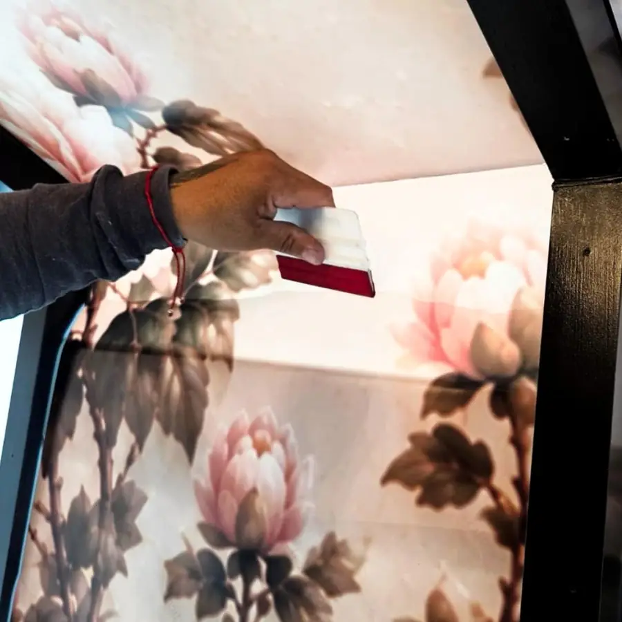 Close-up of a floral wall covering being squeegeed smooth
