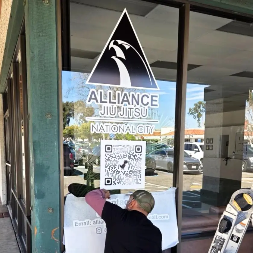 Installer applying an Alliance Jiu Jitsu National City window decal