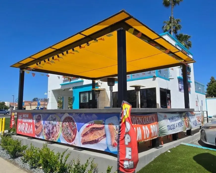 Yellow patio cover with printed menu banners at a taco shop