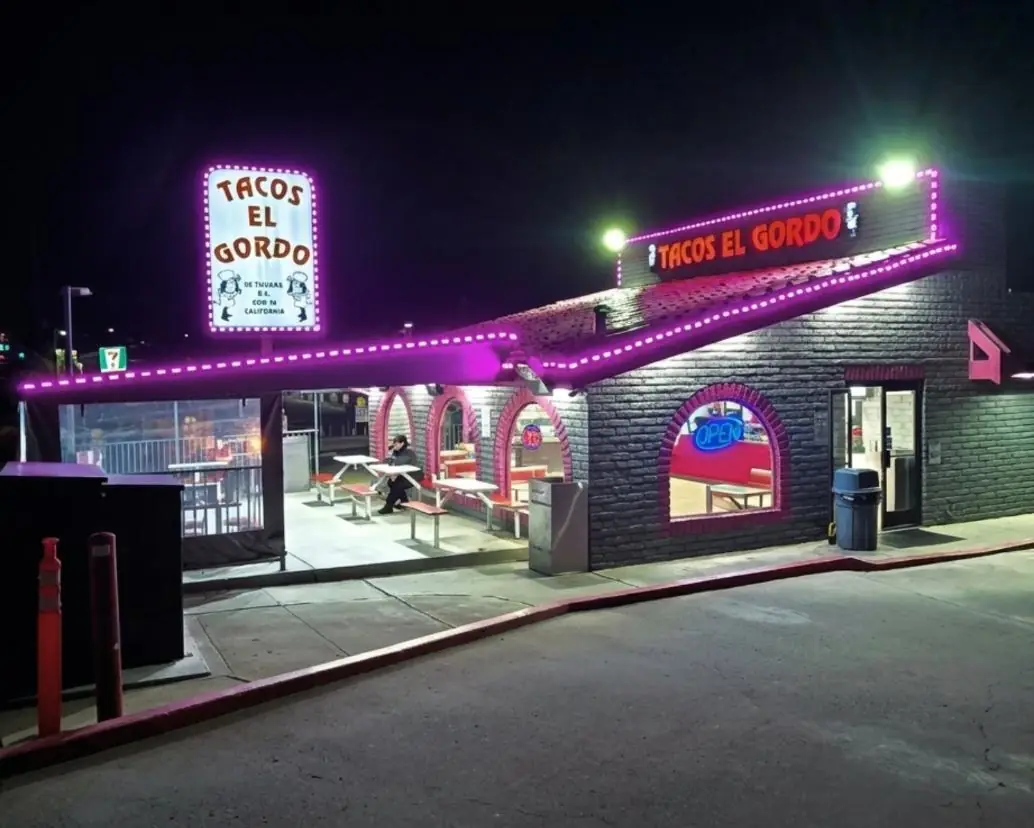 Tacos El Gordo storefront lit at night with a pylon sign and covered patio