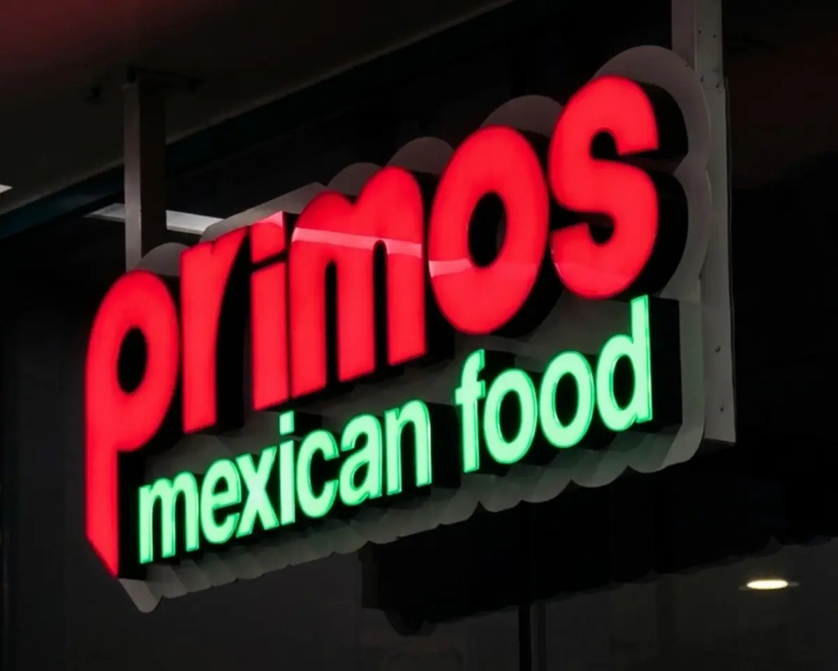 Illuminated Primos Mexican Food channel letters glowing red and green at night