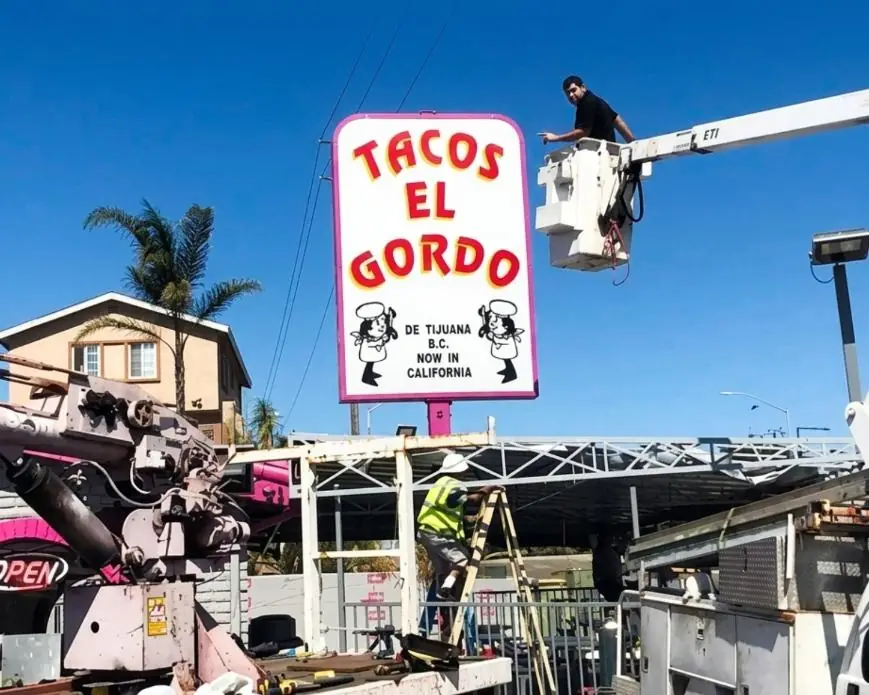 Best Deal crew installing the Tacos El Gordo pylon sign from a boom lift in National City