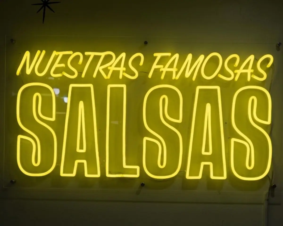 Yellow Nuestras Famosas Salsas neon sign on a restaurant wall