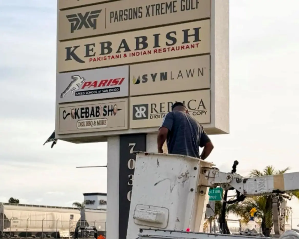 Crew replacing tenant panels on the Miramar Crossings pylon sign from a bucket truck