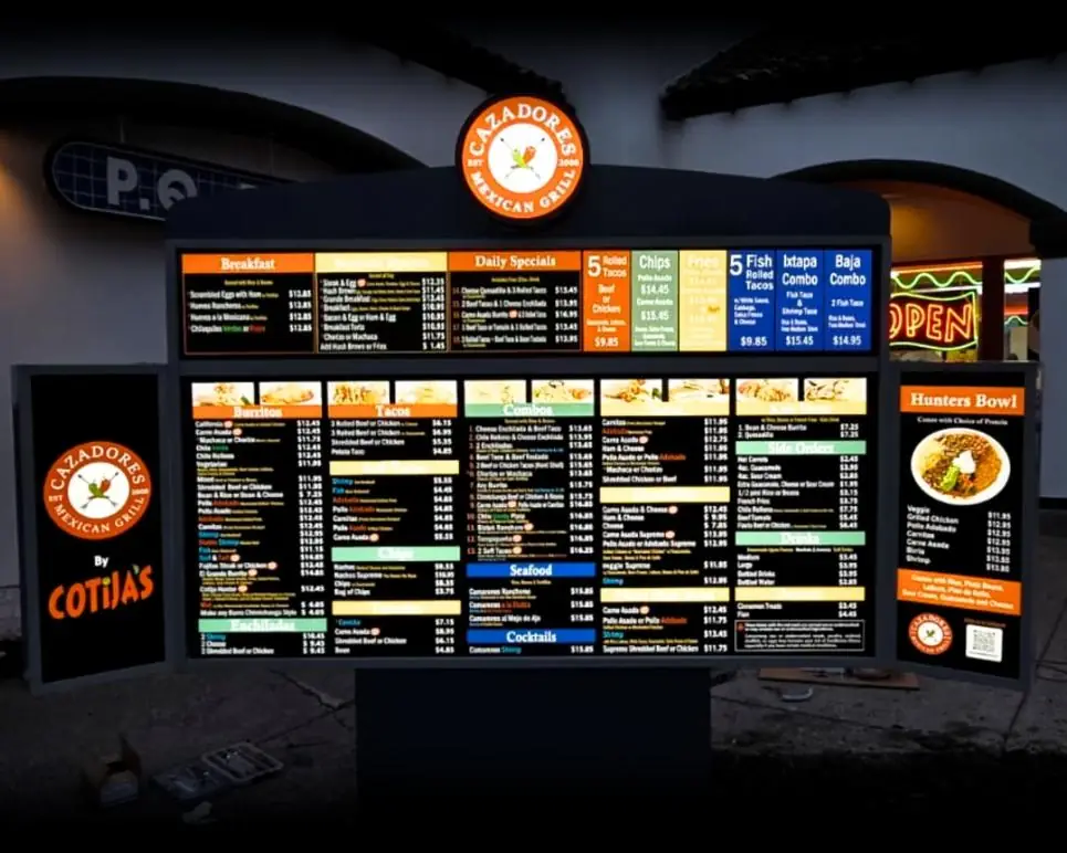 Cazadores by Cotijas lit outdoor menu board at night