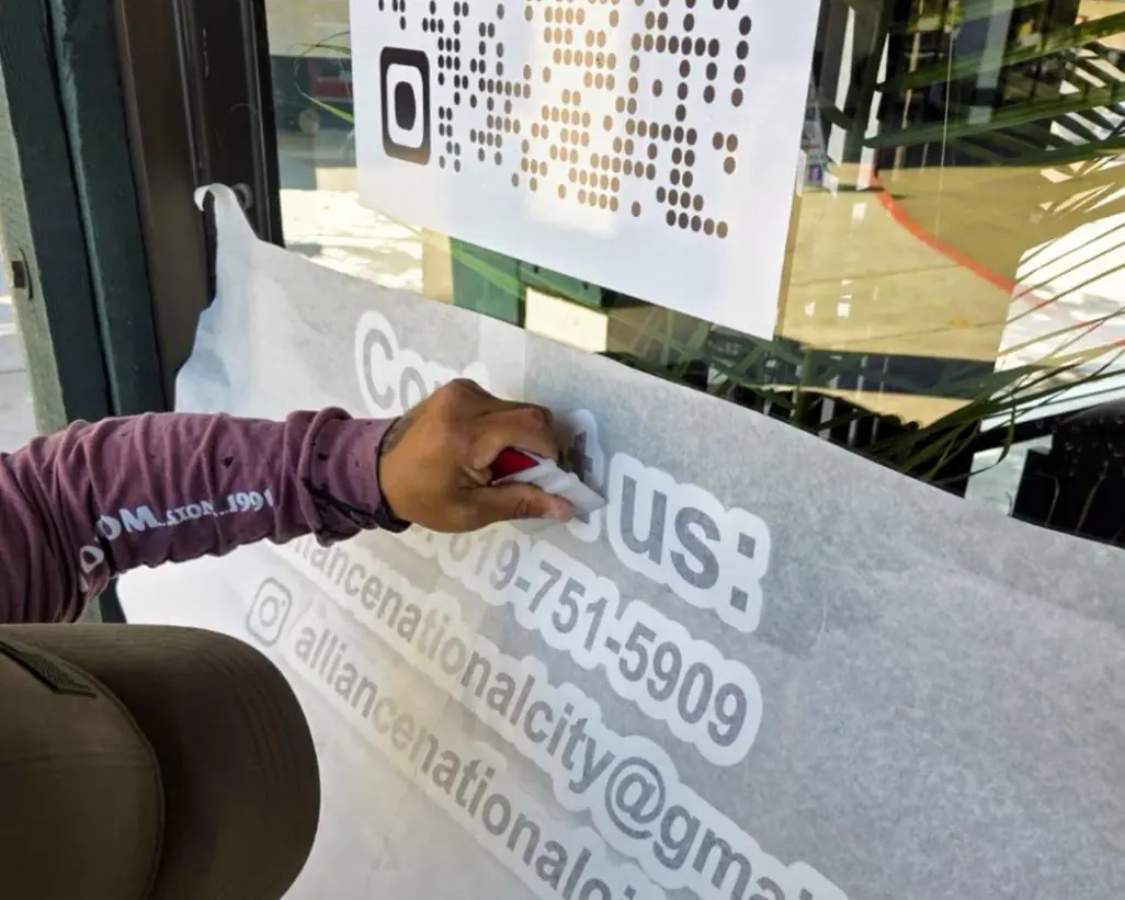 Installer applying contact details in cut vinyl to a glass storefront