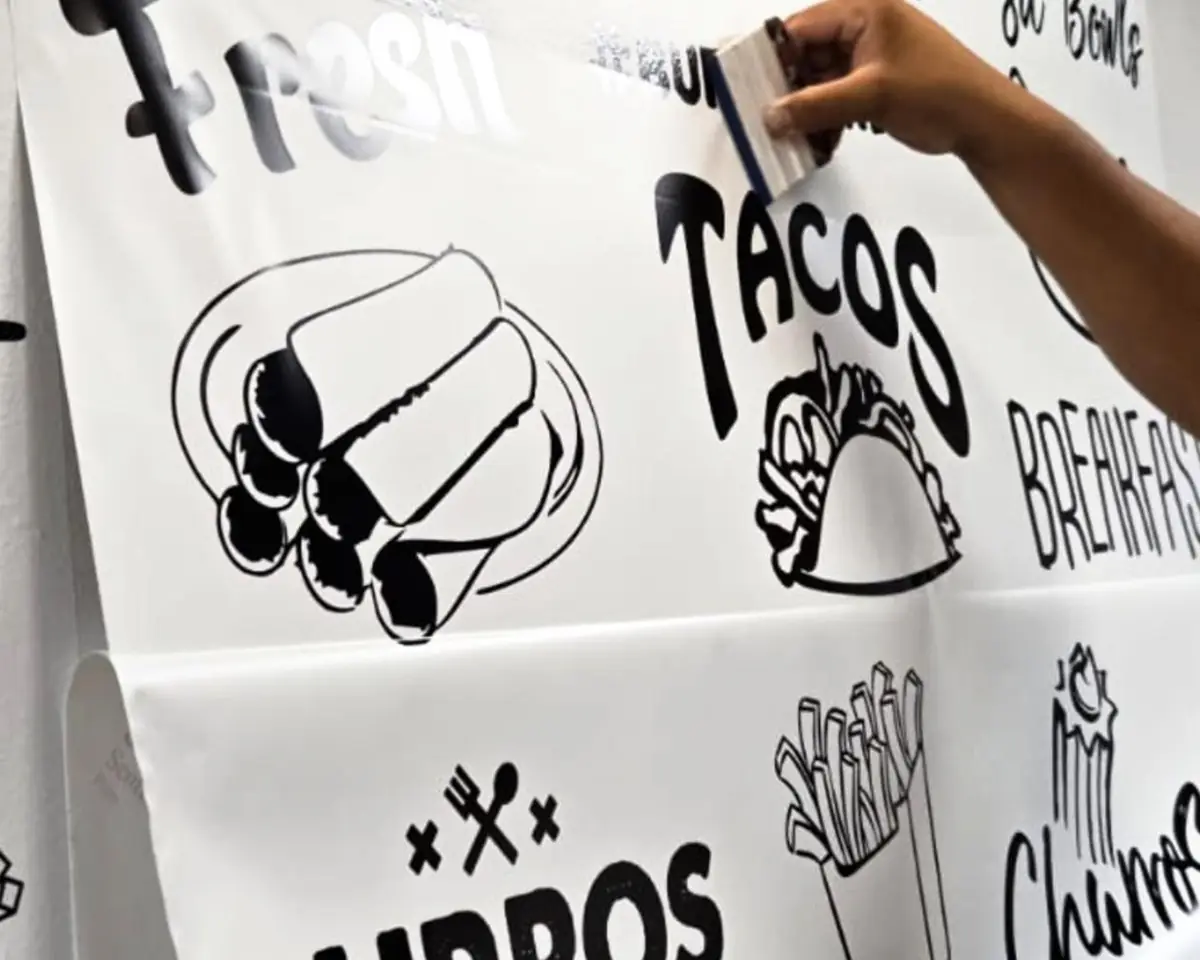 Installer smoothing a large printed decal with taco and burrito artwork