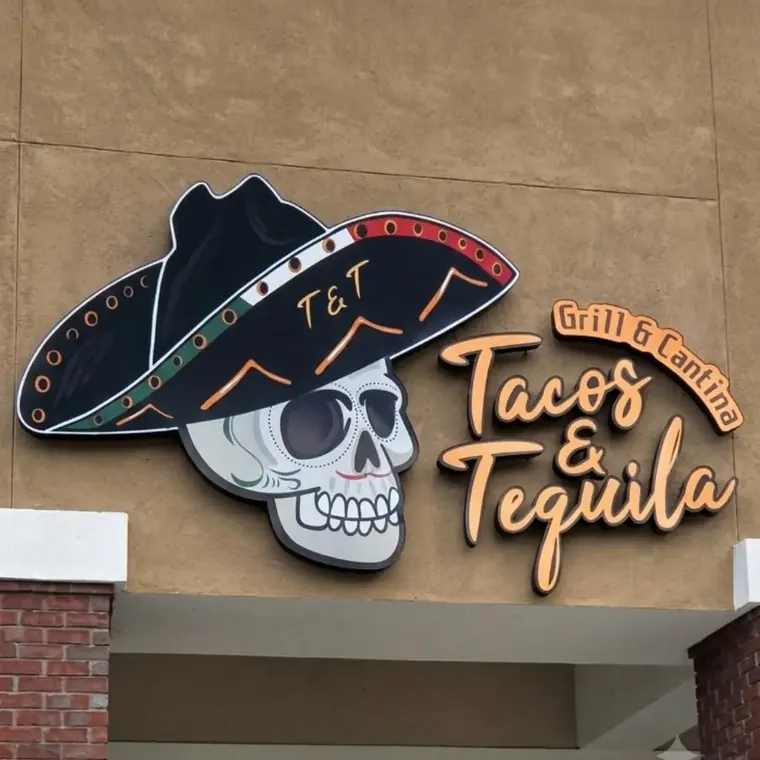 T and T Tacos and Tequila skull and sombrero logo sign on a stucco wall