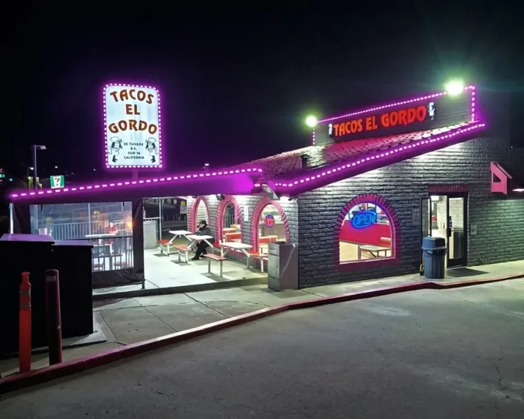 Tacos El Gordo storefront lit at night with a pole sign and covered patio
