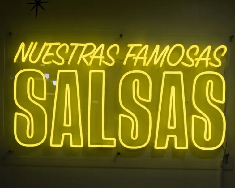Yellow Nuestras Famosas Salsas neon sign on a restaurant wall