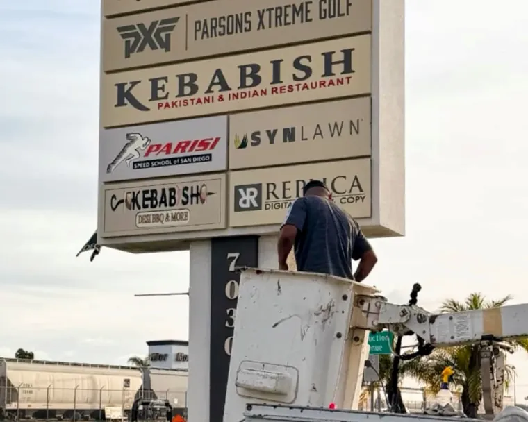 Crew replacing tenant panels on the Miramar Crossings pole sign from a bucket truck